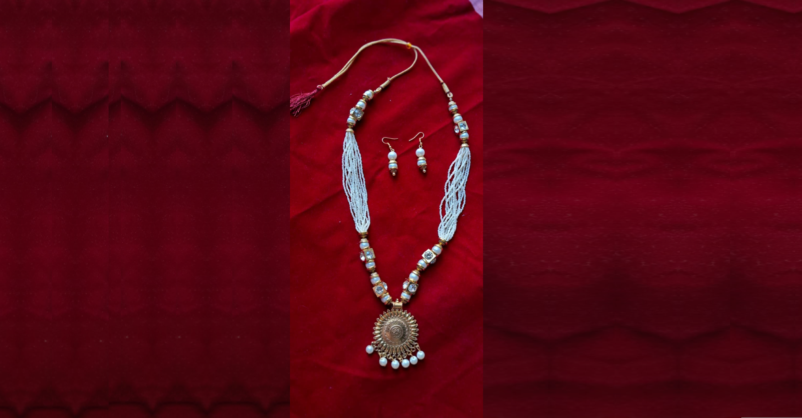 Traditional white beaded necklace set with antique gold round pendant and matching earrings on a red velvet background.