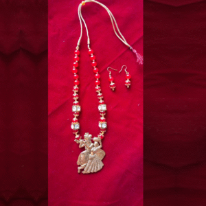Handcrafted red beaded Radha Krishna necklace with matching earrings on red background – traditional Indian jewelry set